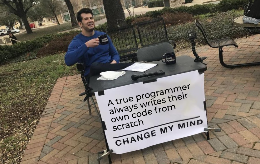 Guy sits at table holding a coffe mug with a sign on the table that says change my mind